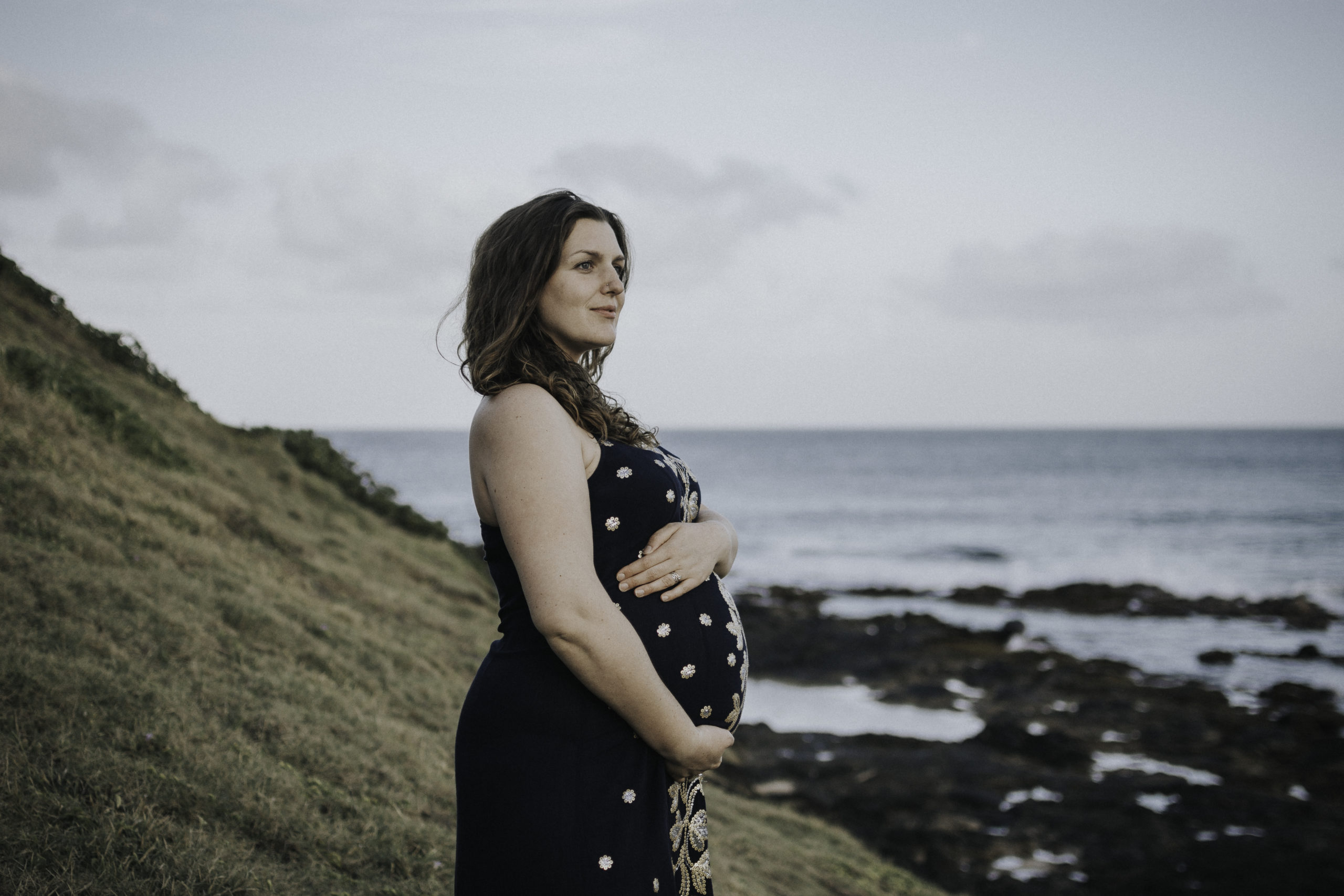Pregnant woman looks at ocean.