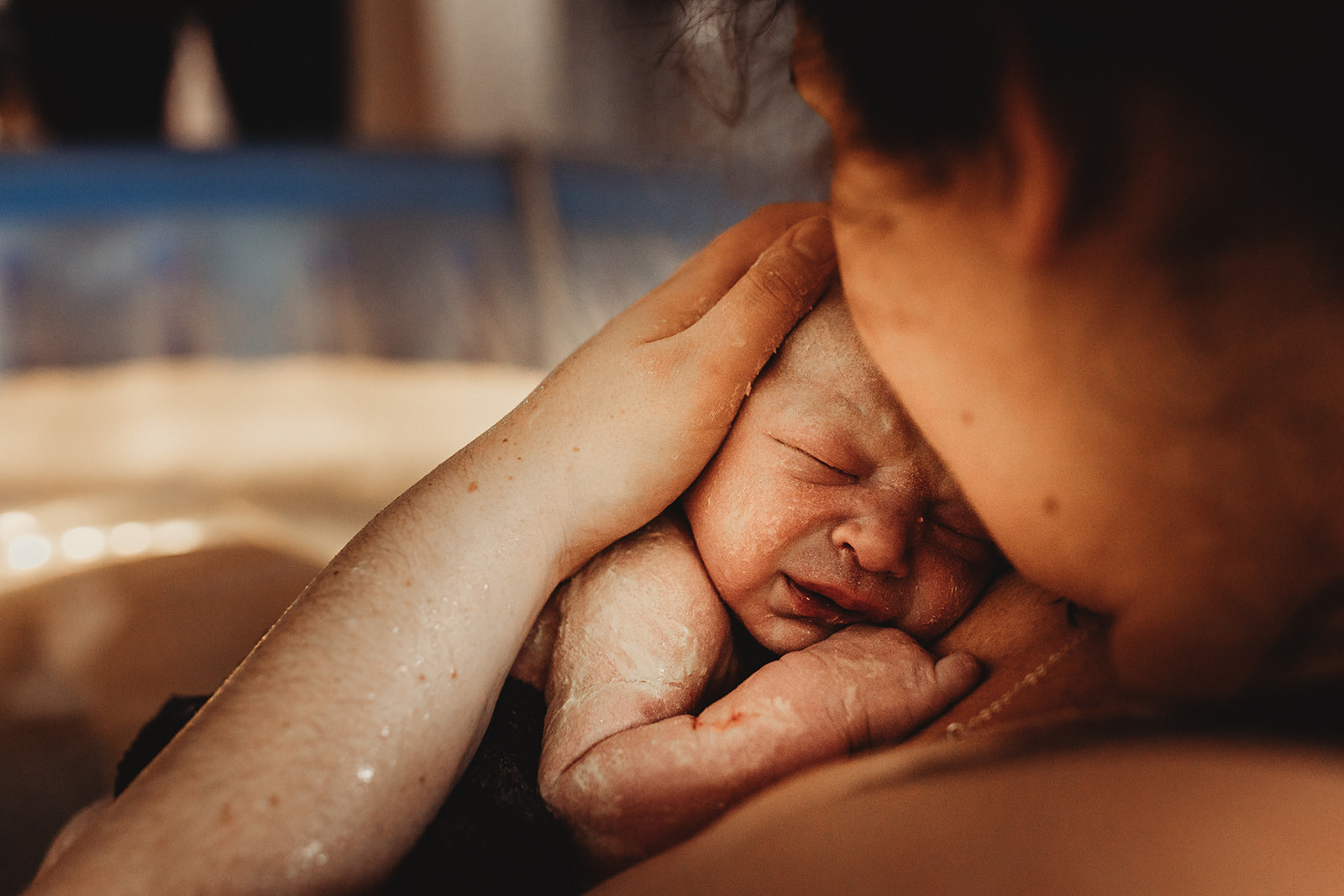 Mom holding a newborn baby in a birth pool